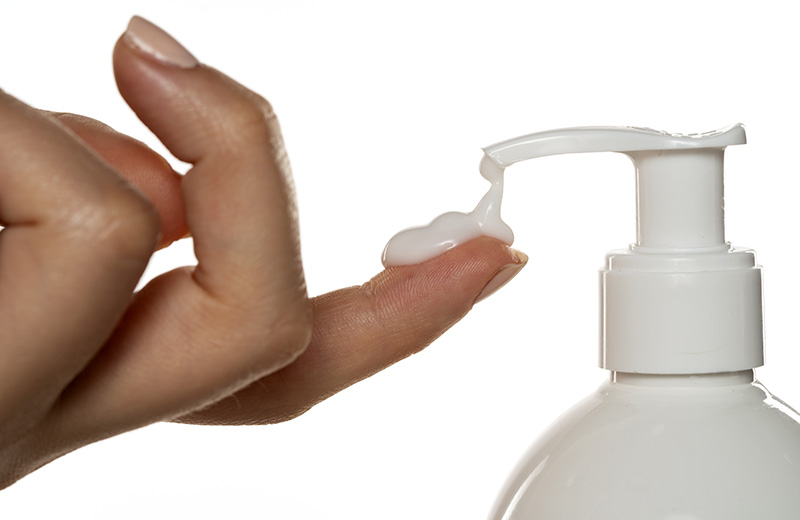 cosmetic product with a pump throws the cream on a woman's finge