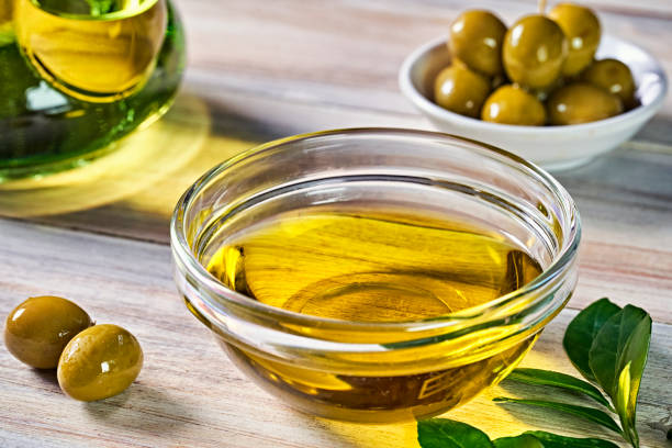 Primer pla d'oli d'oliva en recipient amb olives sobre taula de cuina rústica