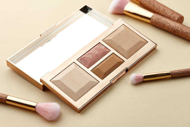Make up palette at brush sa beige background, close up view