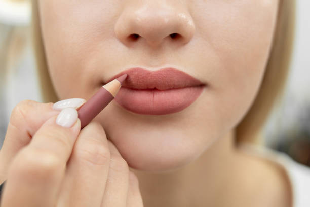 Maquiagem labial.Close de uma cosmetologista pintando os lábios com um lápis após a maquiagem definitiva.